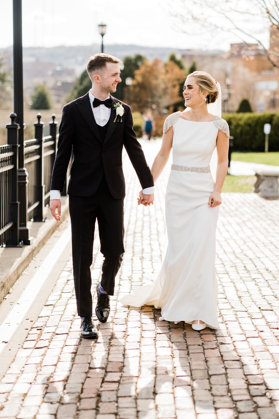 Couple walking hand-in-hand on the cobblestone path beside the historic iron fence — downtown Duluth portrait — Tim Larsen Photography, Duluth MN