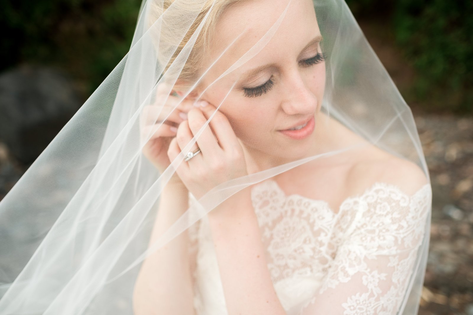Tender close portrait of the bride through her draped veil, eyes downcast, engagement ring visible — Tim Larsen Photography, Duluth MN