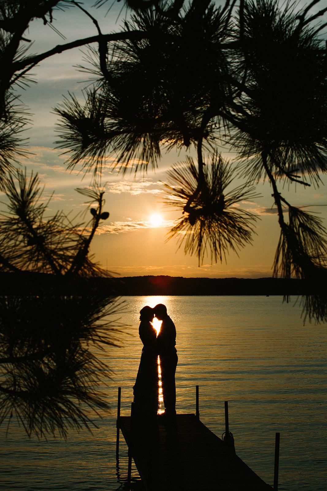 Couple silhouette on the dock at sunset — pine trees framing Gull Lake — Tim Larsen Photography, Brainerd Lakes MN
