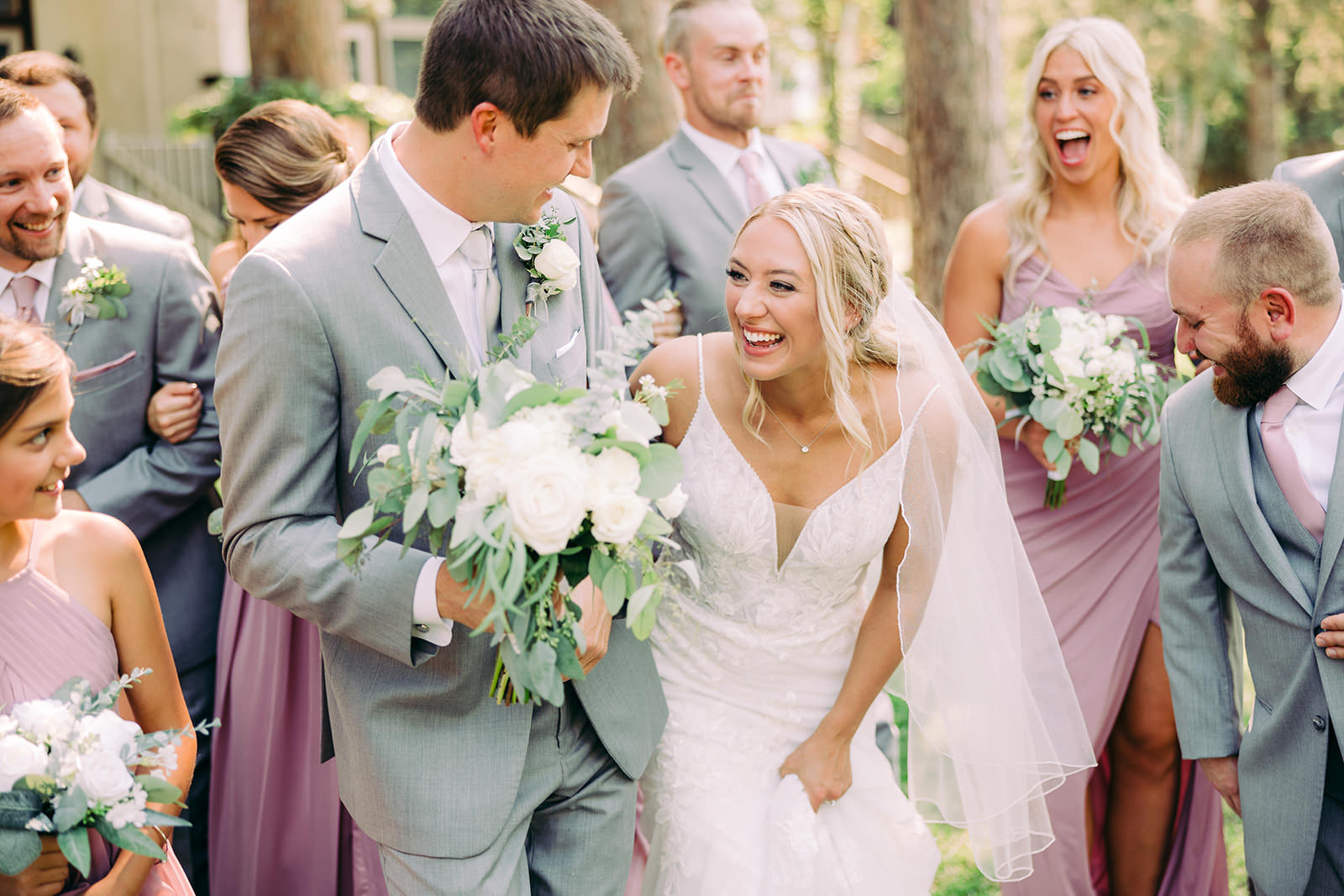 Couple walking through the wedding party — sage and mauve dresses with white bouquets — Tim Larsen Photography, Brainerd Lakes MN