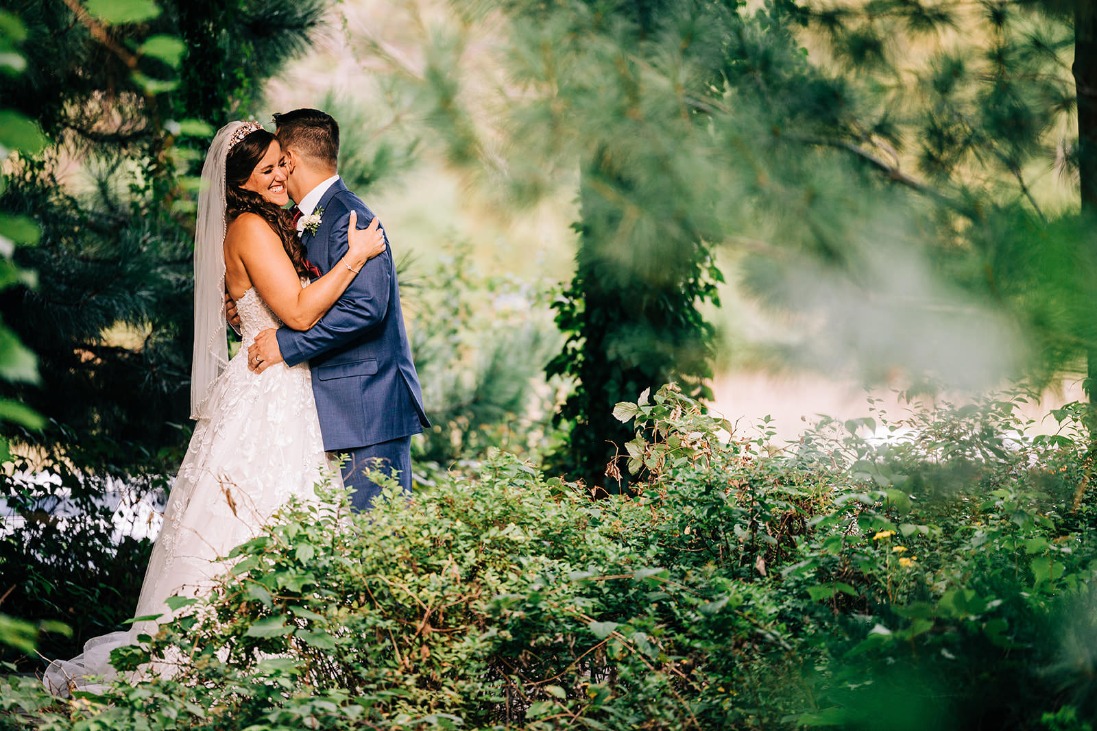 Couple kissing in the lush garden at Manhattan Beach Lodge — soft light through the trees — Tim Larsen Photography, Brainerd Lakes MN