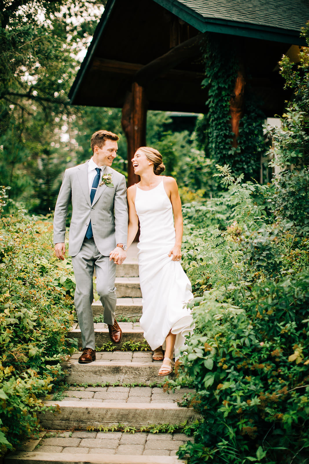 Couple laughing walking down the stone steps through the garden at the lodge — Tim Larsen Photography, Brainerd Lakes MN
