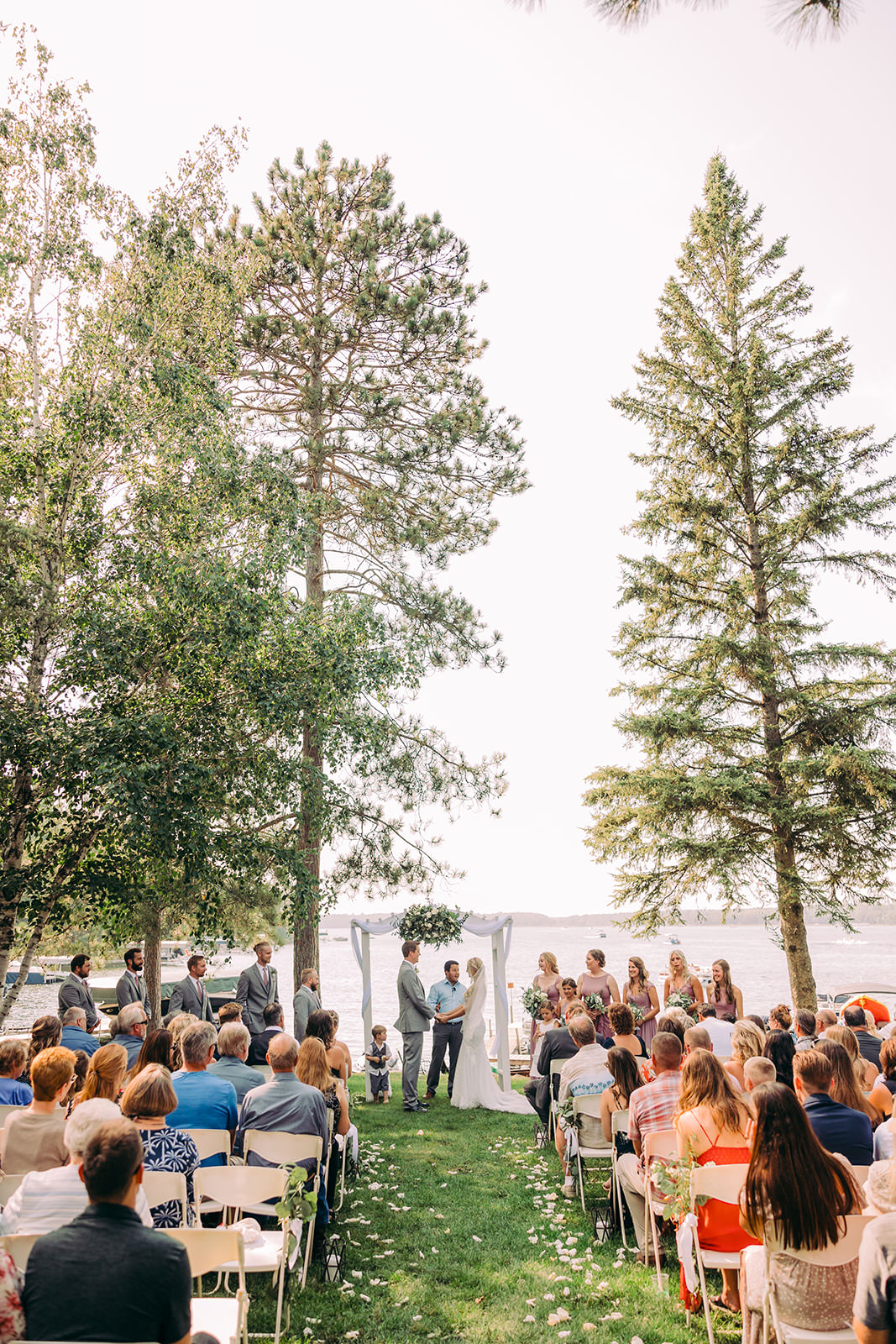 Lakeside ceremony between tall pines — intimate gathering on the lodge lawn — Tim Larsen Photography, Brainerd Lakes MN