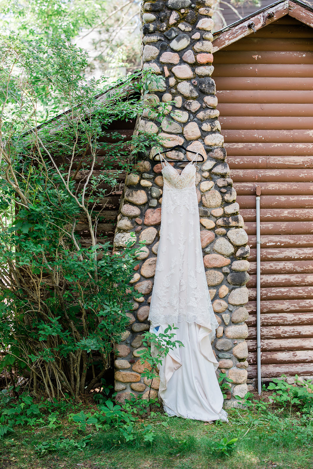 Wedding dress hanging on the stone chimney with ivy at Manhattan Beach Lodge — Tim Larsen Photography, Brainerd Lakes MN
