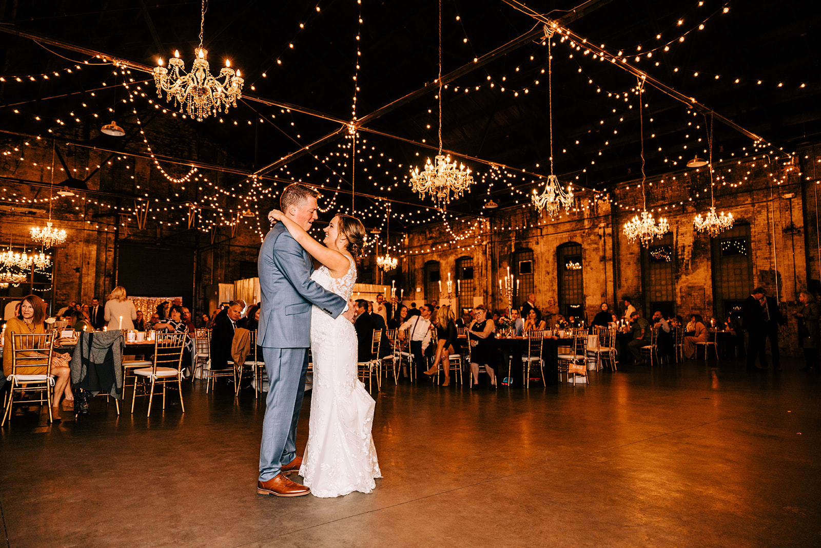 First dance under chandeliers and string lights in Blacksmith Main — Tim Larsen Photography, Brainerd Lakes MN