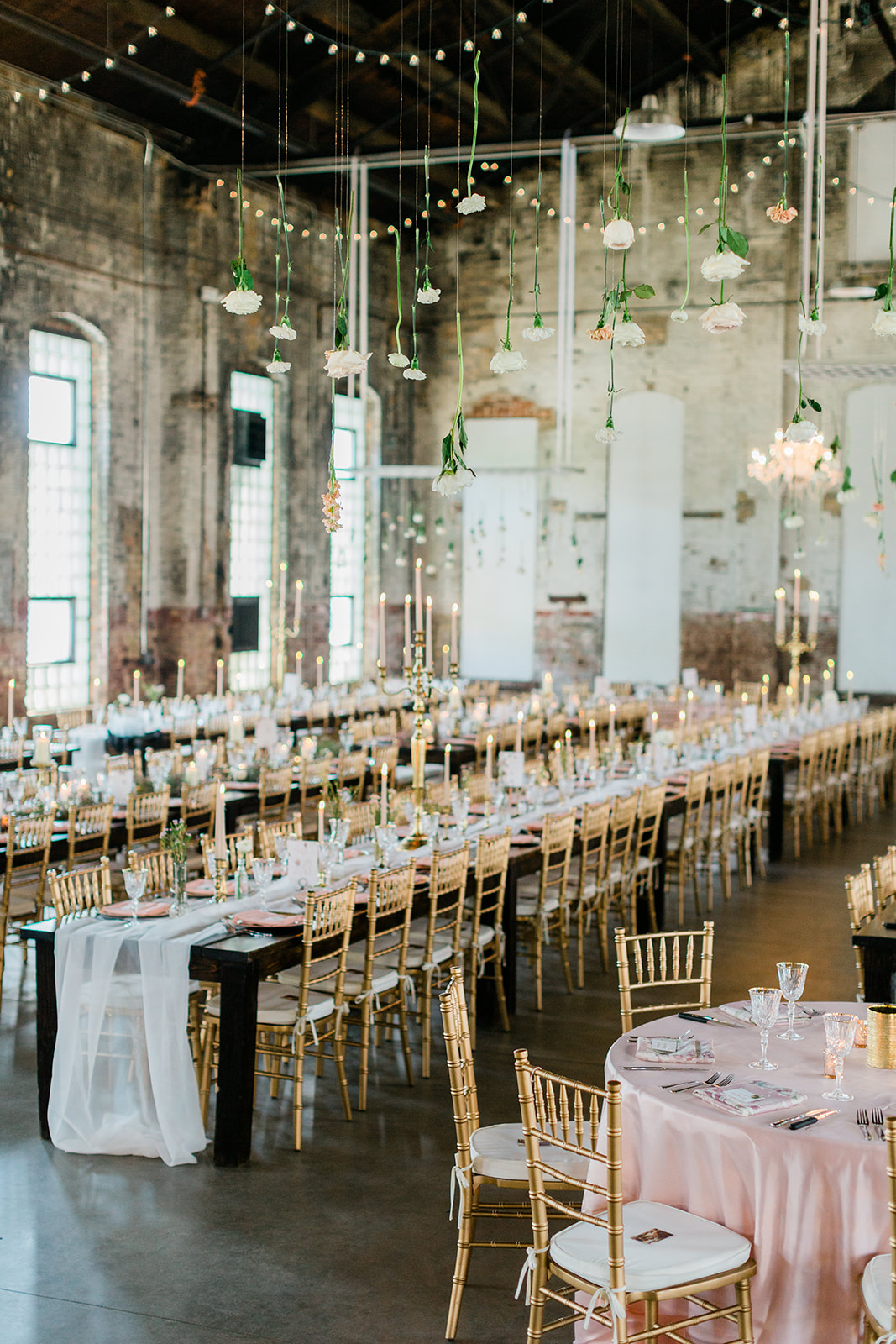 Reception tablescape in Three Main — long tables, gold chairs, hanging florals, string lights — Tim Larsen Photography, Brainerd Lakes MN
