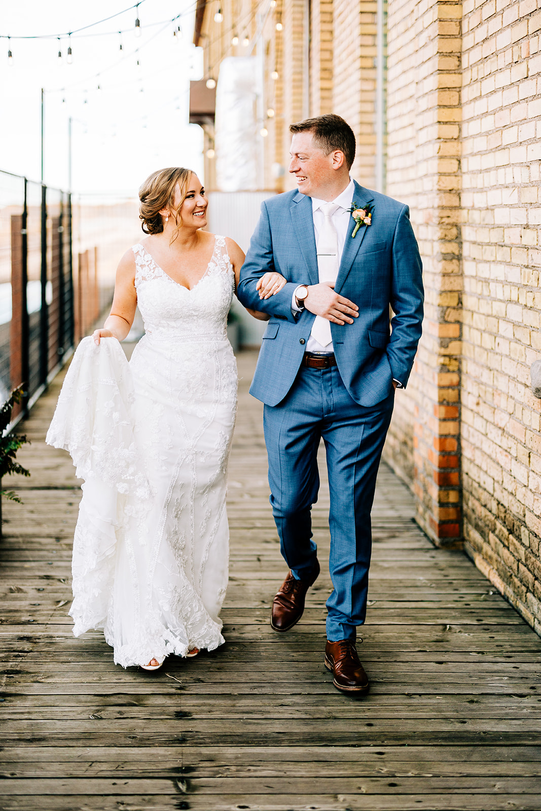 Couple laughing walking on the wooden boardwalk outside the brick building — Tim Larsen Photography, Brainerd Lakes MN