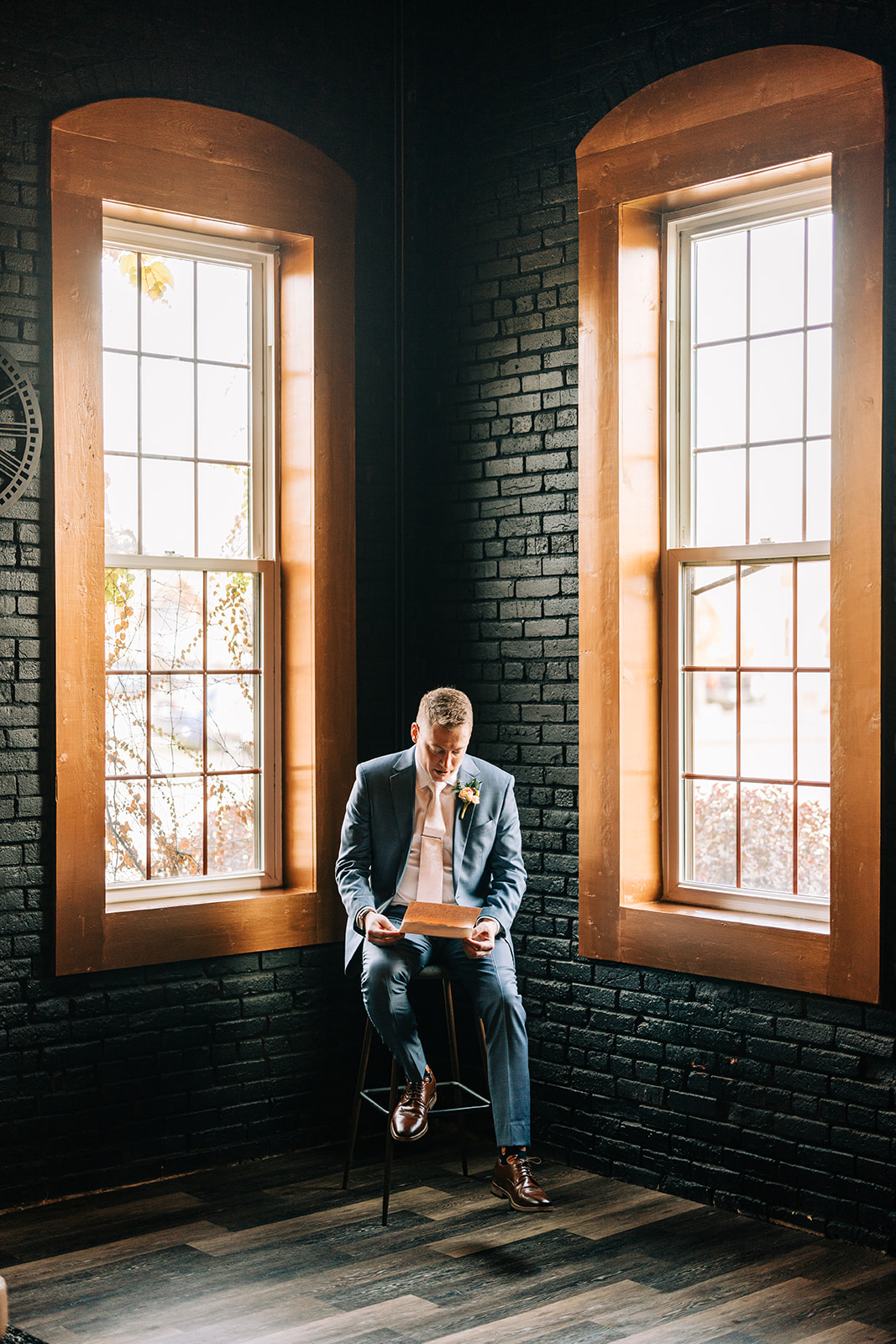 Groom reading letter between arched windows with warm light — moody portrait — Tim Larsen Photography, Brainerd Lakes MN