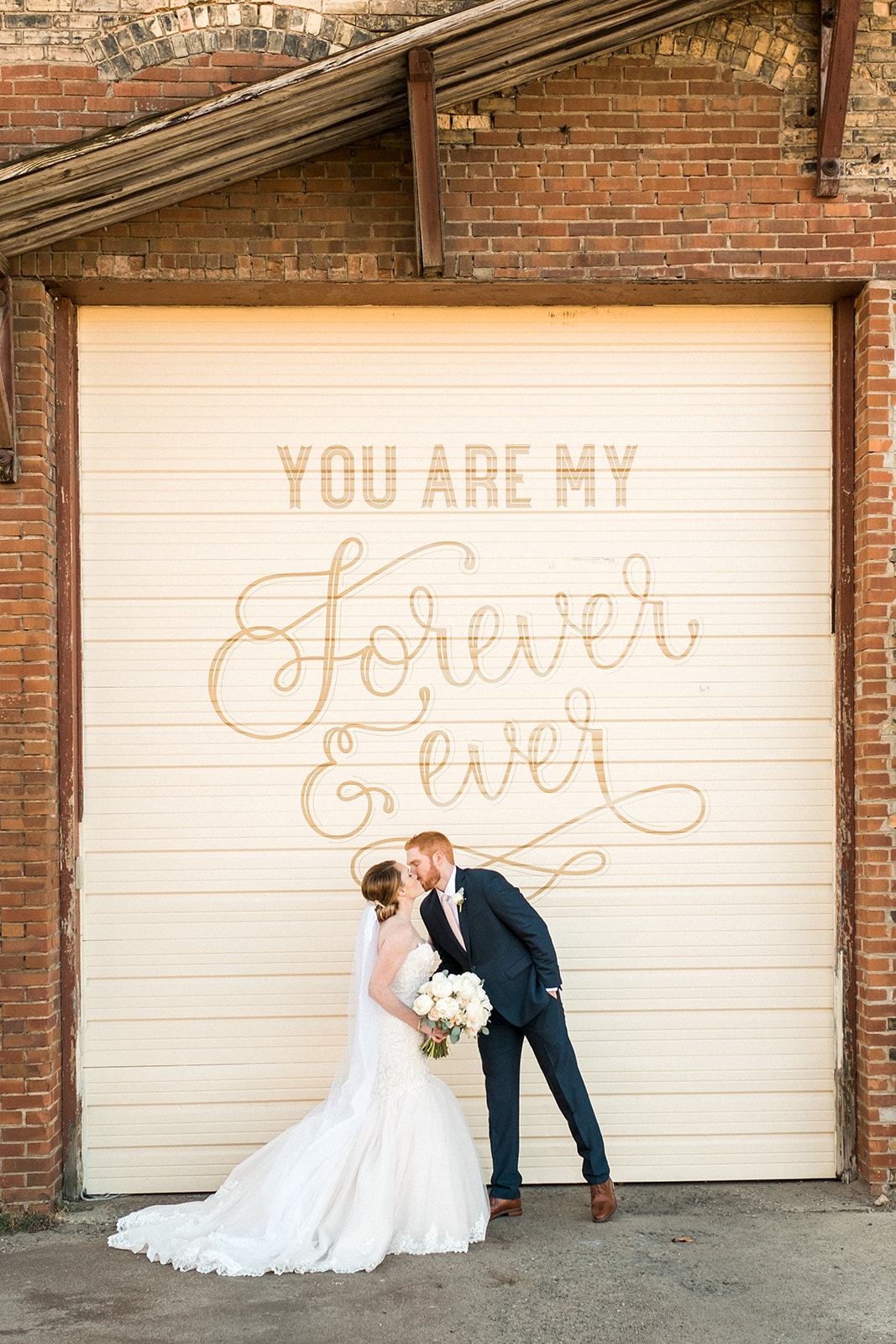 Couple kissing by the You Are My Forever & Ever mural on the white garage door — Tim Larsen Photography, Brainerd Lakes MN
