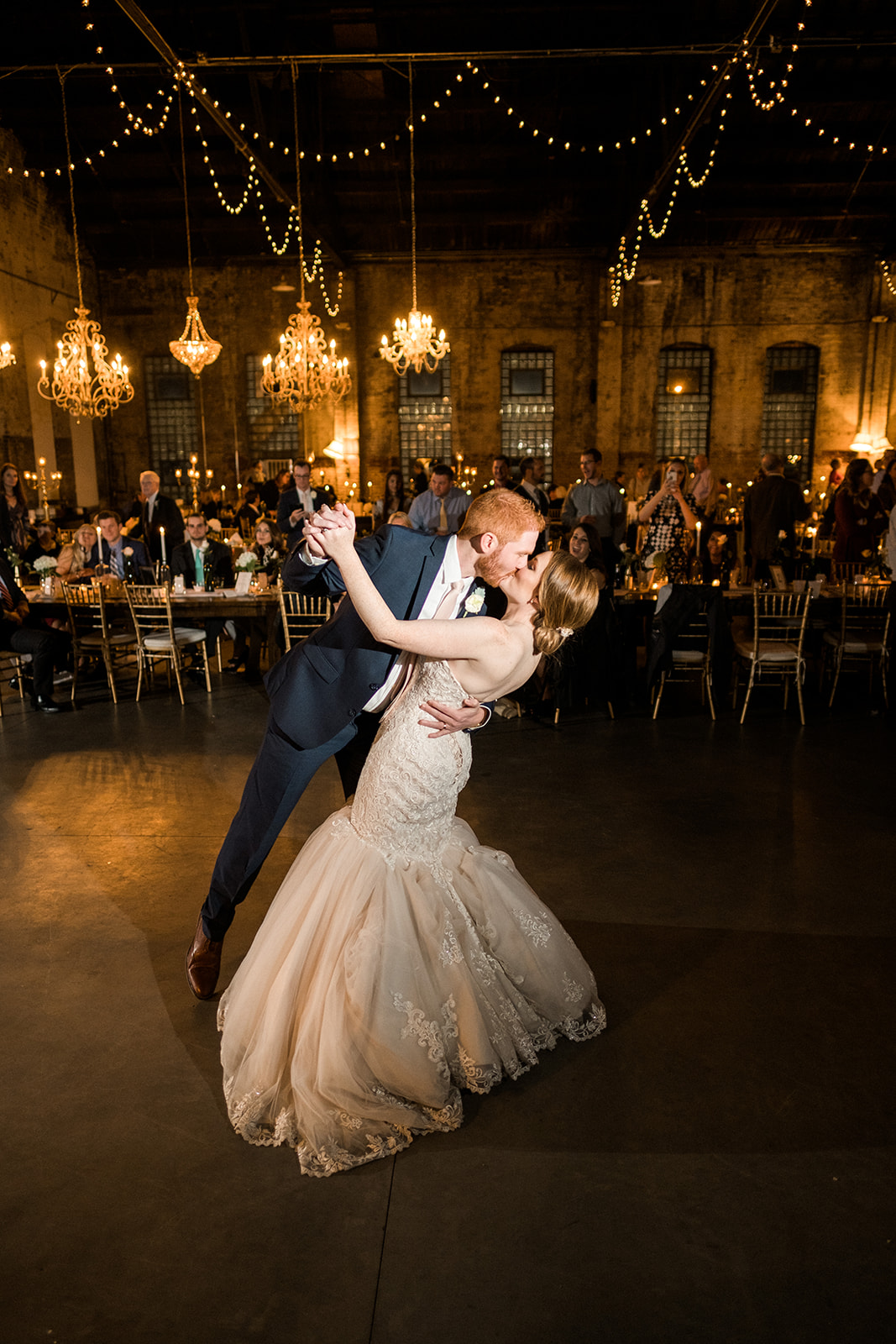 First dance dip in Blacksmith Main — chandeliers and string lights above — Tim Larsen Photography, Brainerd Lakes MN