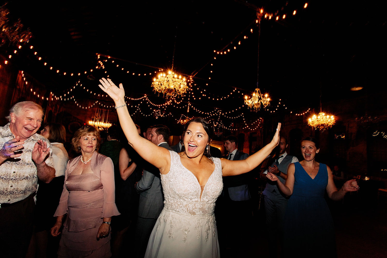 Bride dancing with arms up on the dance floor — chandeliers and string lights — Tim Larsen Photography, Brainerd Lakes MN