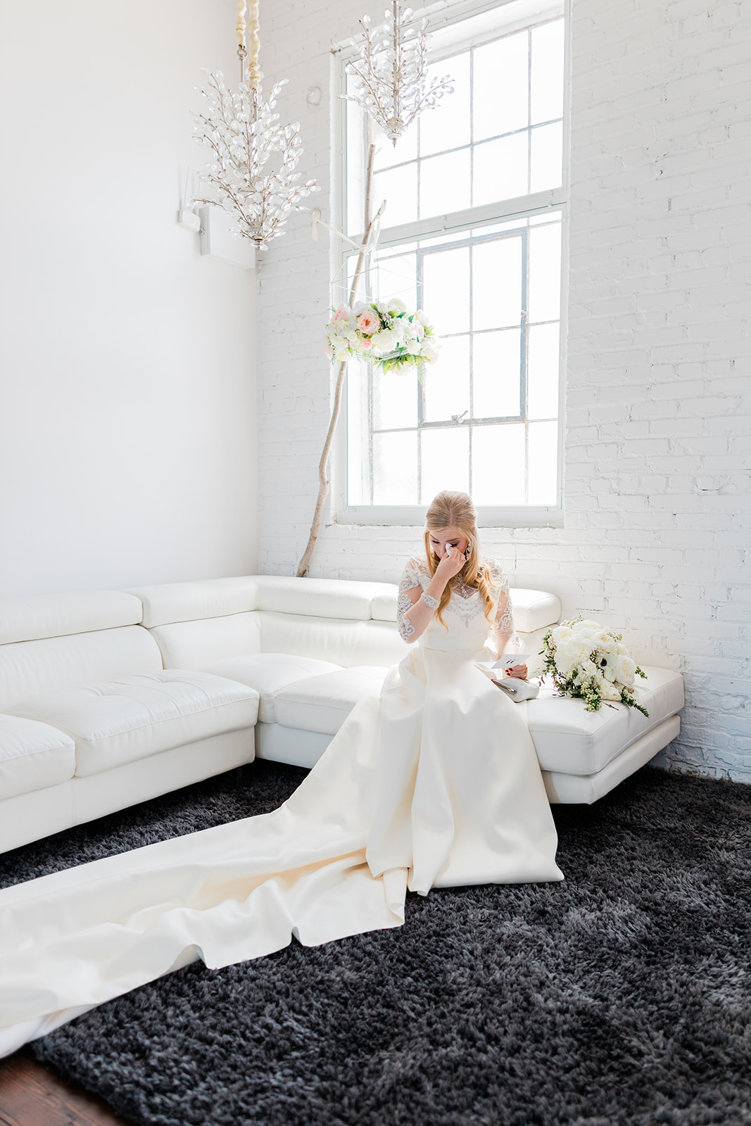 Bride sitting on white couch in the bridal suite reading her vows — natural light — Tim Larsen Photography, Brainerd Lakes MN