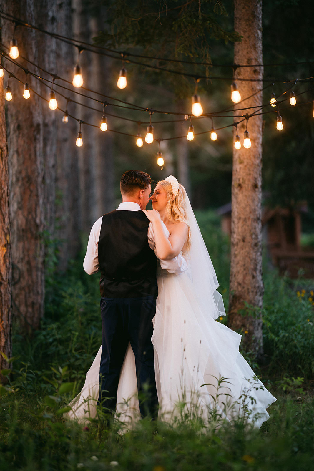 Couple kissing under string lights in the pine forest at dusk — Tim Larsen Photography, Brainerd Lakes MN