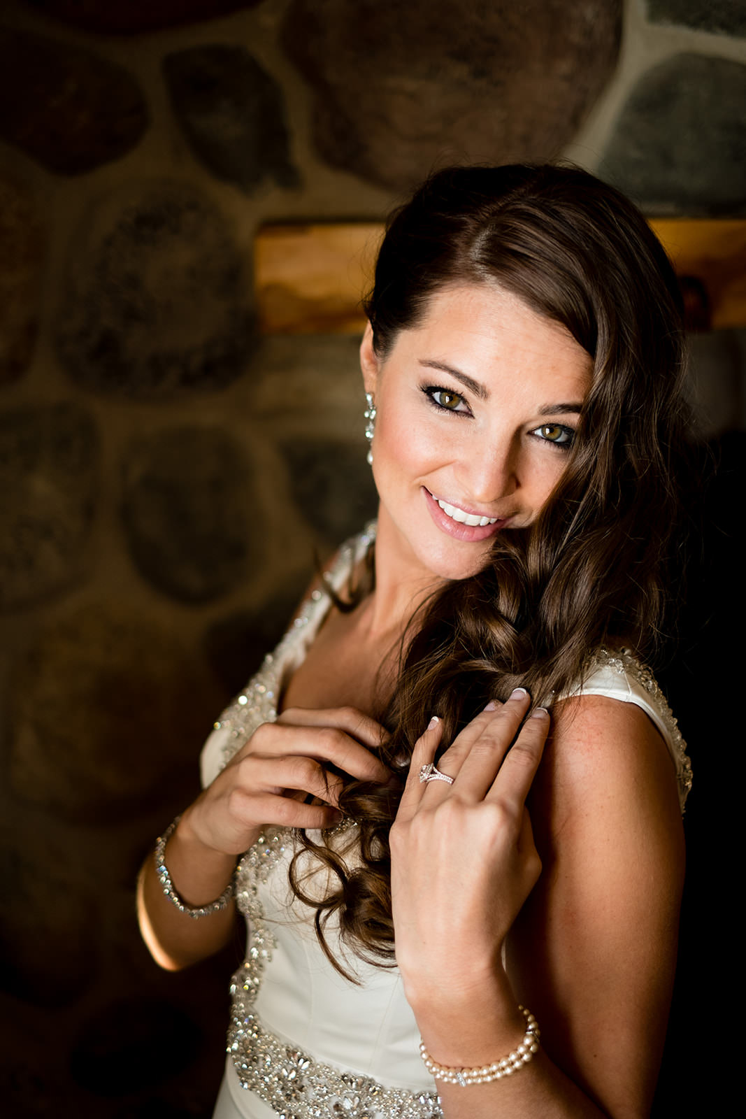 Bridal portrait by the stone fireplace — warm light on lace and jewelry — Tim Larsen Photography, Brainerd Lakes MN