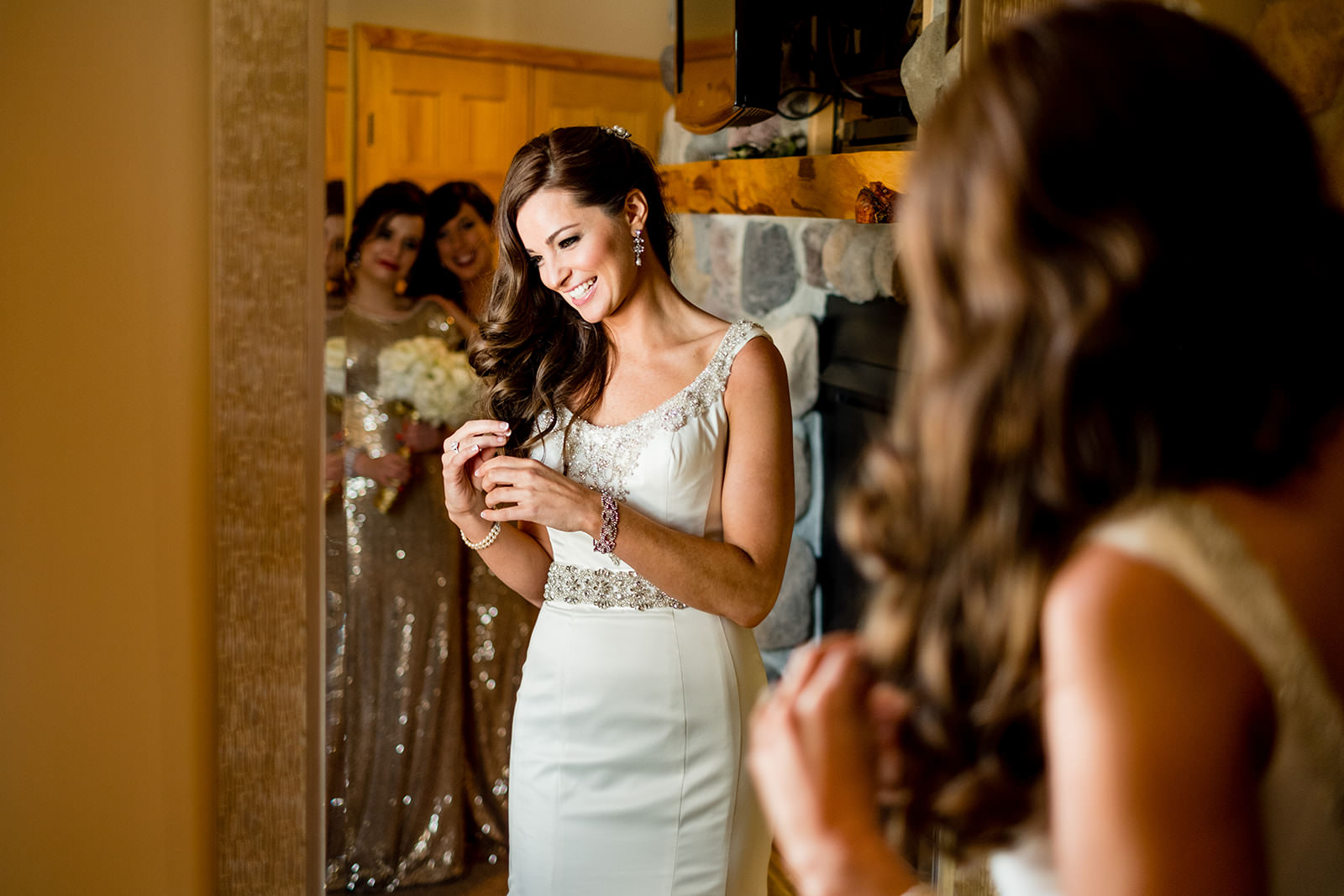 Bride getting ready with bridesmaids by the stone fireplace — warm light — Tim Larsen Photography, Brainerd Lakes MN
