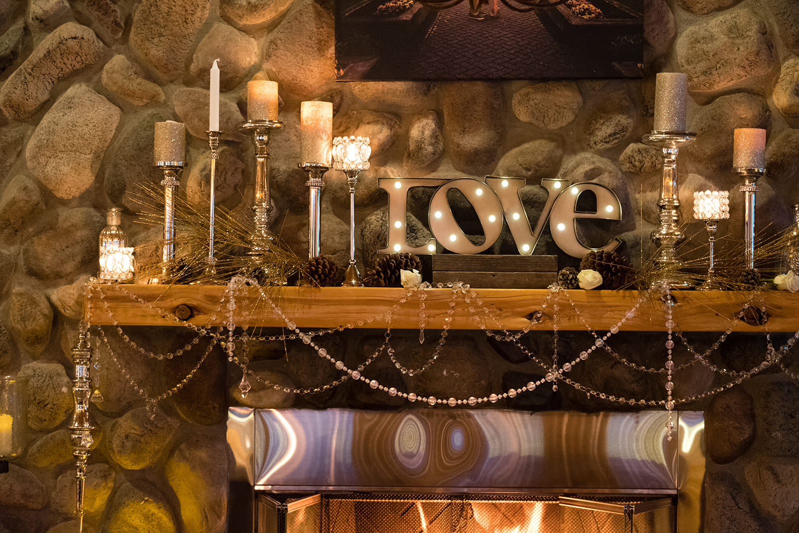 LOVE letters and candles on the stone fireplace mantel — reception detail at Pine Peaks — Tim Larsen Photography, Brainerd Lakes MN