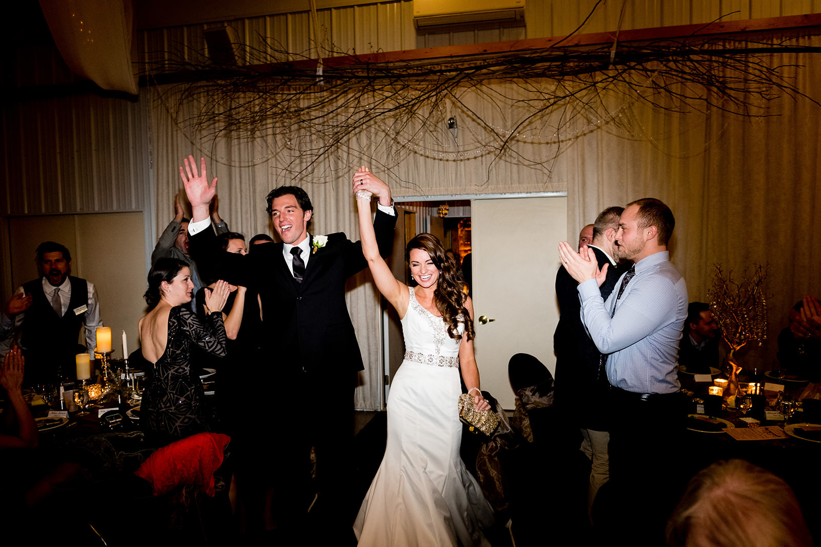 Grand entrance — couple raising hands on the dance floor with guests cheering — Tim Larsen Photography, Brainerd Lakes MN