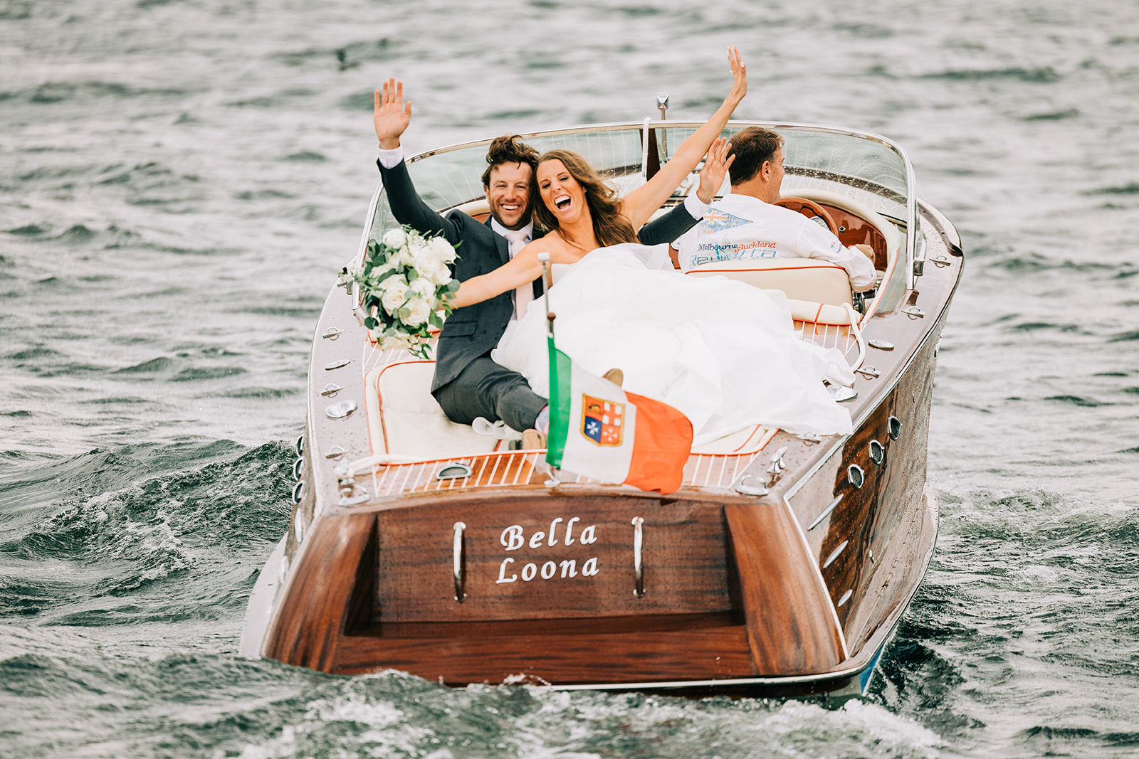 Couple celebrating on the back of a wooden boat on the lake — Tim Larsen Photography, Brainerd Lakes MN