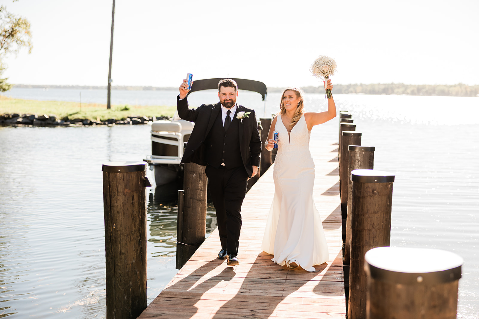 Couple cheering walking down the dock with the lake behind them — Tim Larsen Photography, Brainerd Lakes MN