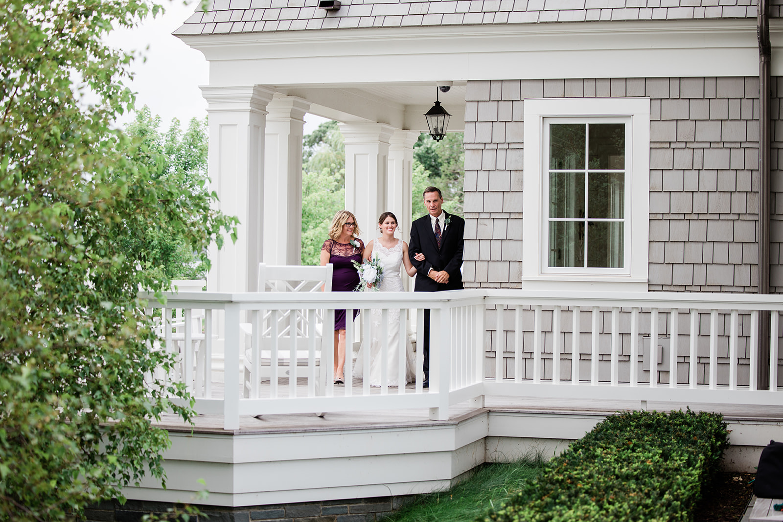 Couple and family member standing on the porch of a white lake house — Tim Larsen Photography, Brainerd Lakes MN