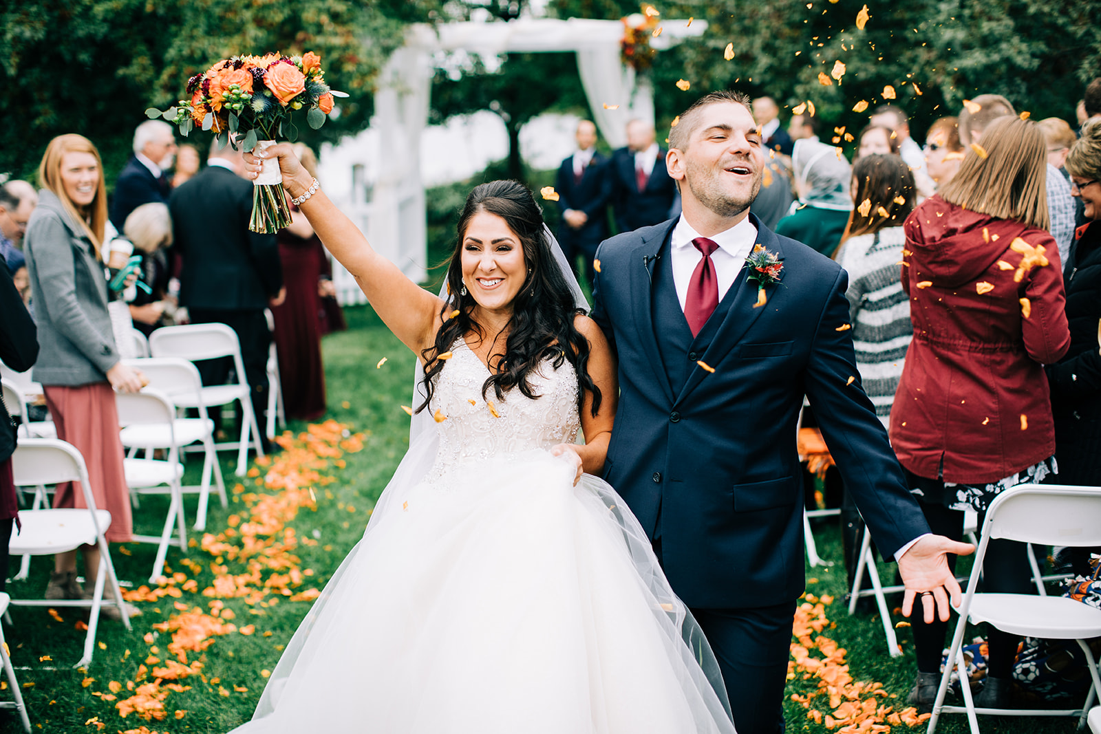 Couple celebrating recessional as guests toss petals on an autumn lawn — Tim Larsen Photography, Brainerd Lakes MN