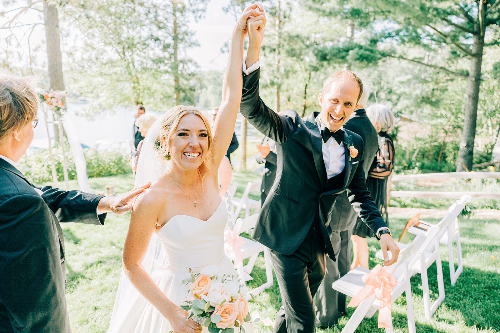 Couple raising hands in celebration walking back down the outdoor aisle — Tim Larsen Photography, Brainerd Lakes MN