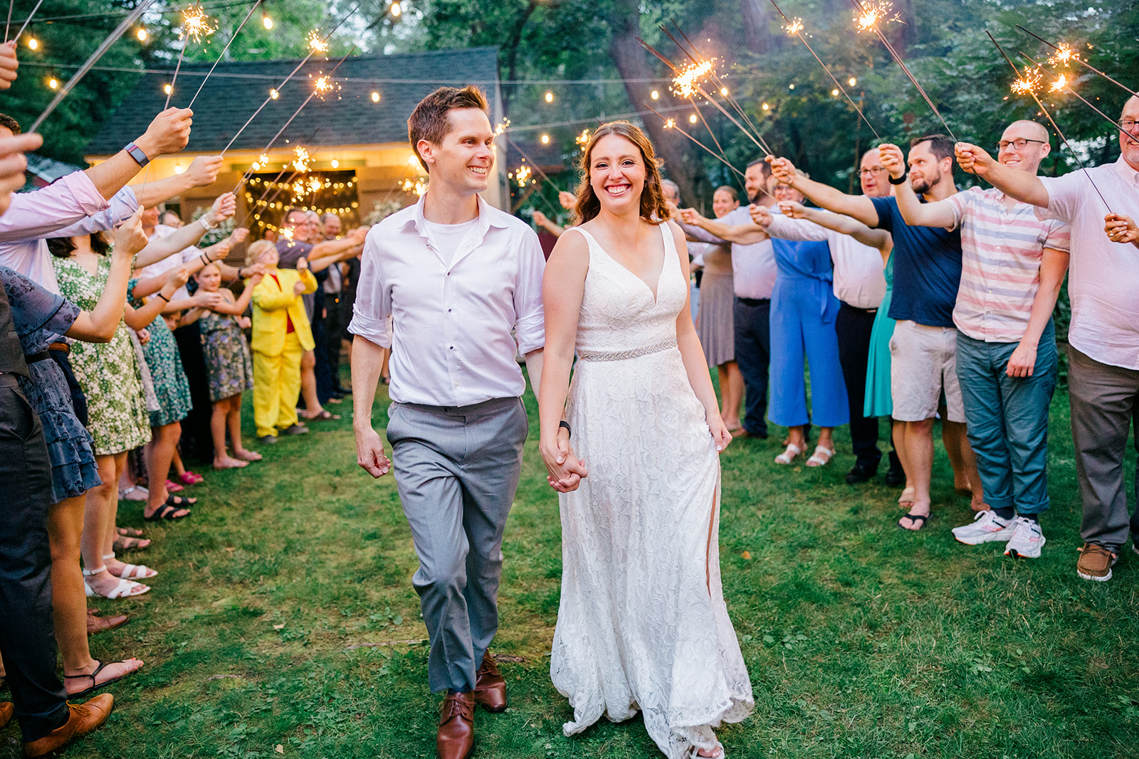 Sparkler exit with guests lining the path under string lights at night — Tim Larsen Photography, Brainerd Lakes MN