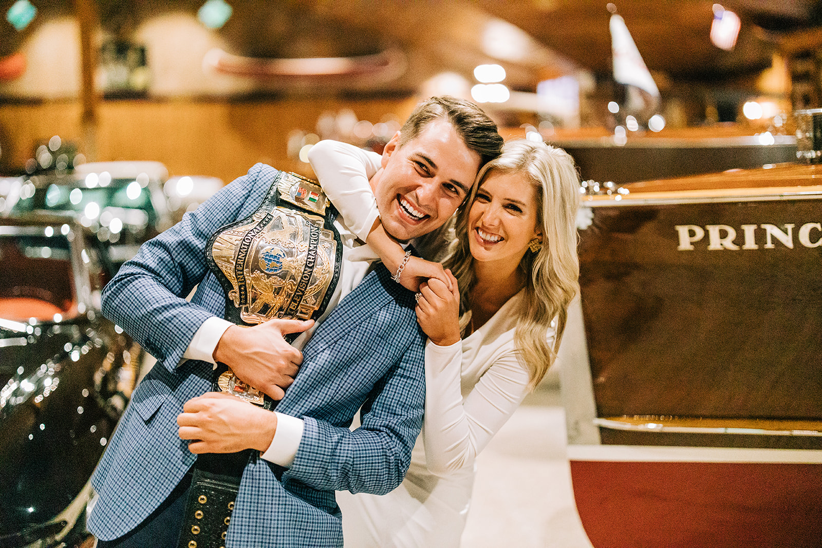 Couple laughing together with a championship belt inside a vintage boathouse — Tim Larsen Photography, Brainerd Lakes MN