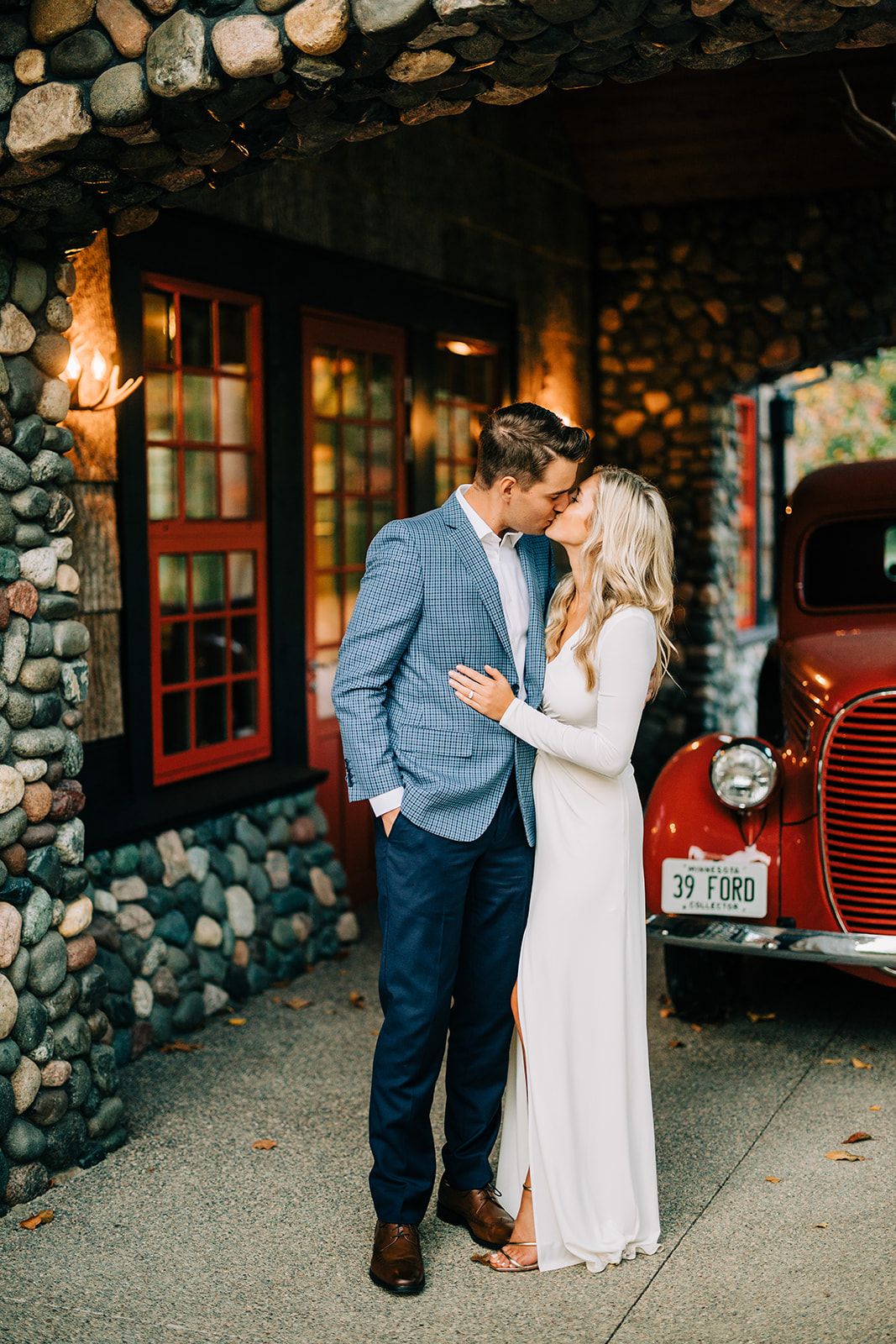 Couple kissing by a vintage Ford truck outside a stone lake cabin — Tim Larsen Photography, Brainerd Lakes MN