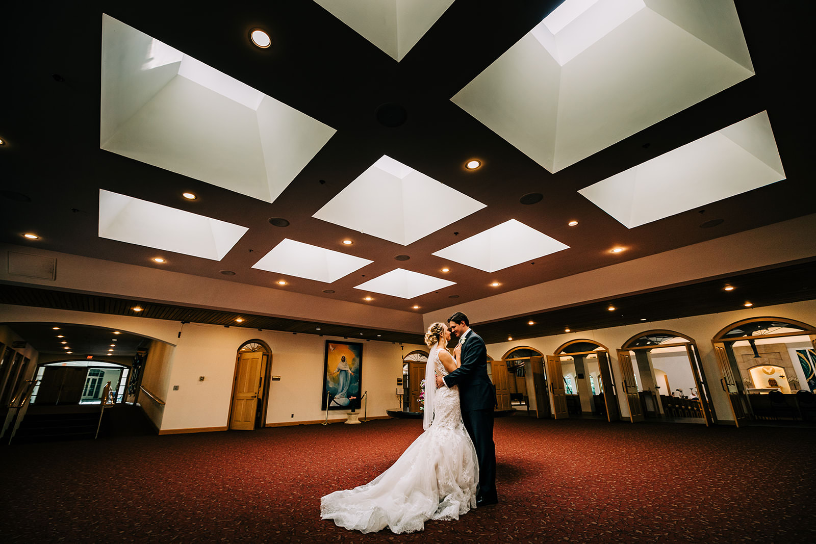 Couple kissing in a grand lobby with geometric skylights and red carpet — Twin Cities wedding — Tim Larsen Photography, Brainerd Lakes MN