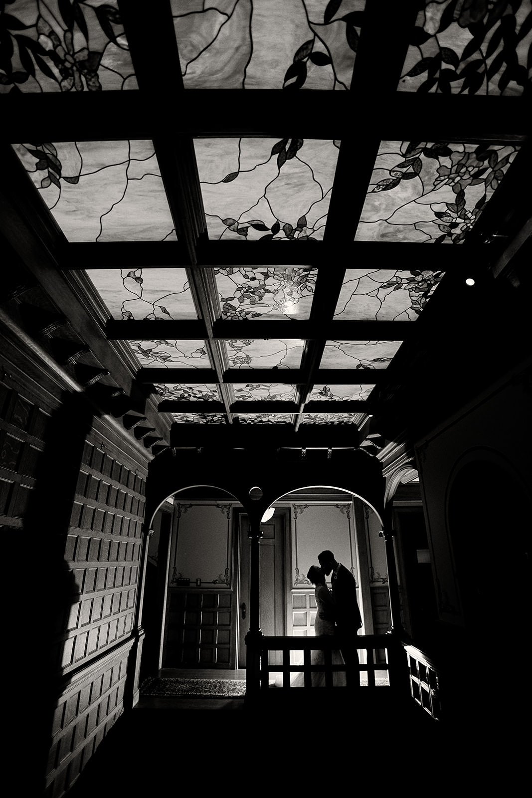 Couple silhouetted under a stained glass ceiling in black and white — historic Twin Cities venue — Tim Larsen Photography, Brainerd Lakes MN