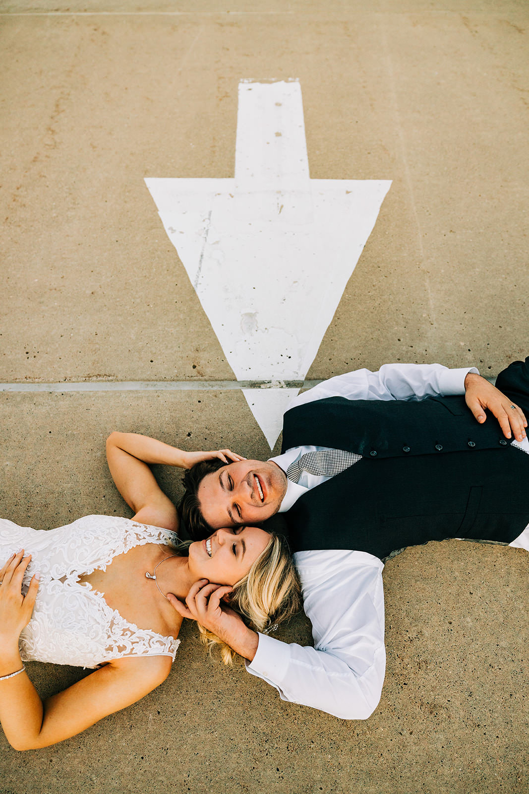 Couple lying on pavement with a painted arrow — overhead engagement portrait in Minneapolis — Tim Larsen Photography, Brainerd Lakes MN