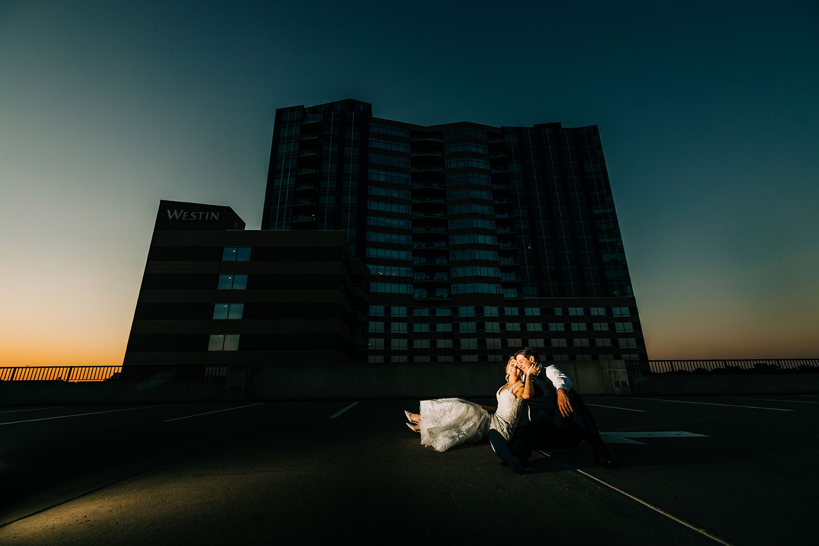 Couple sitting on a rooftop parking ramp at twilight with the Westin hotel behind them — Tim Larsen Photography, Brainerd Lakes MN
