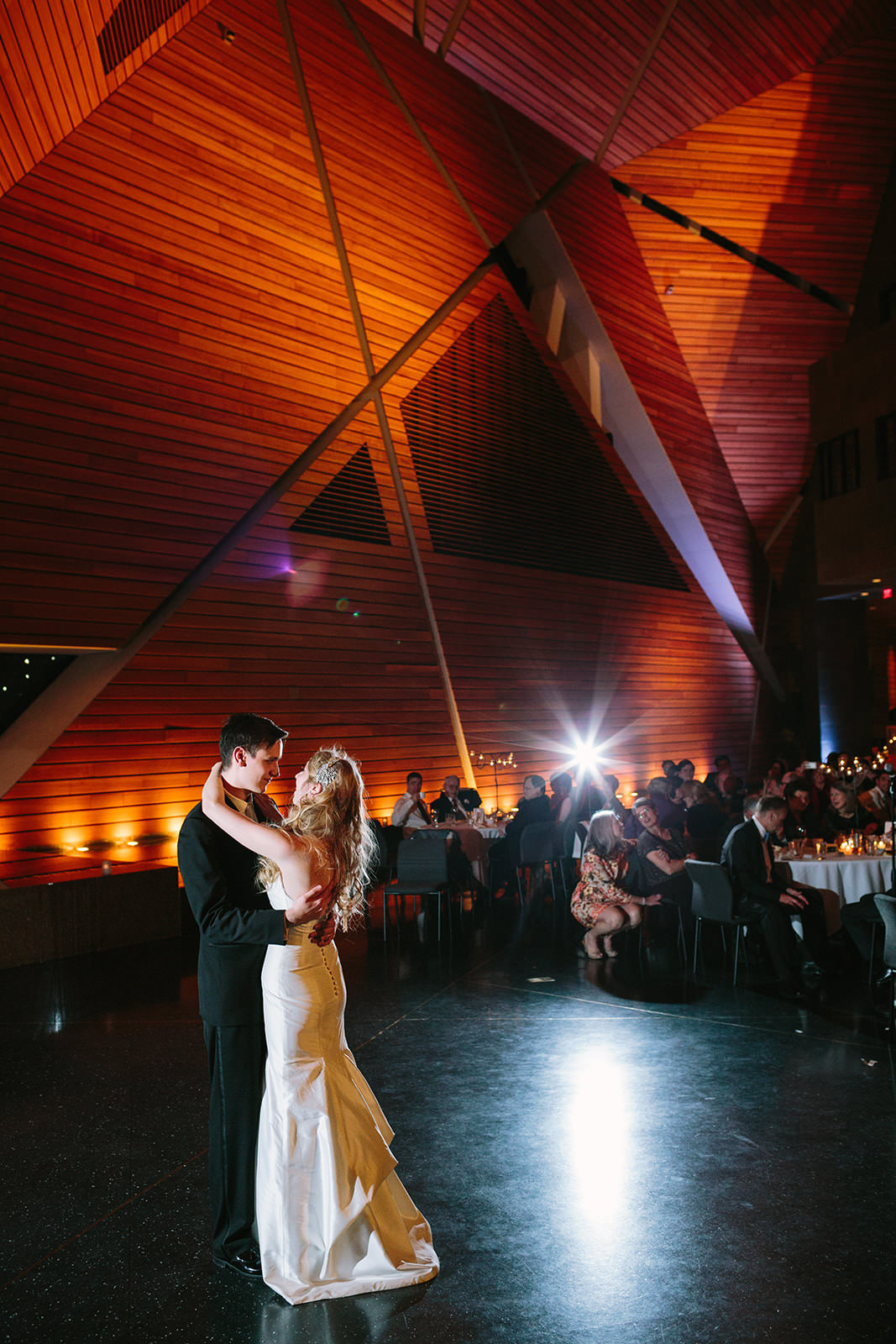 First dance under angular wooden ceiling with warm amber uplighting — Minneapolis reception — Tim Larsen Photography, Brainerd Lakes MN