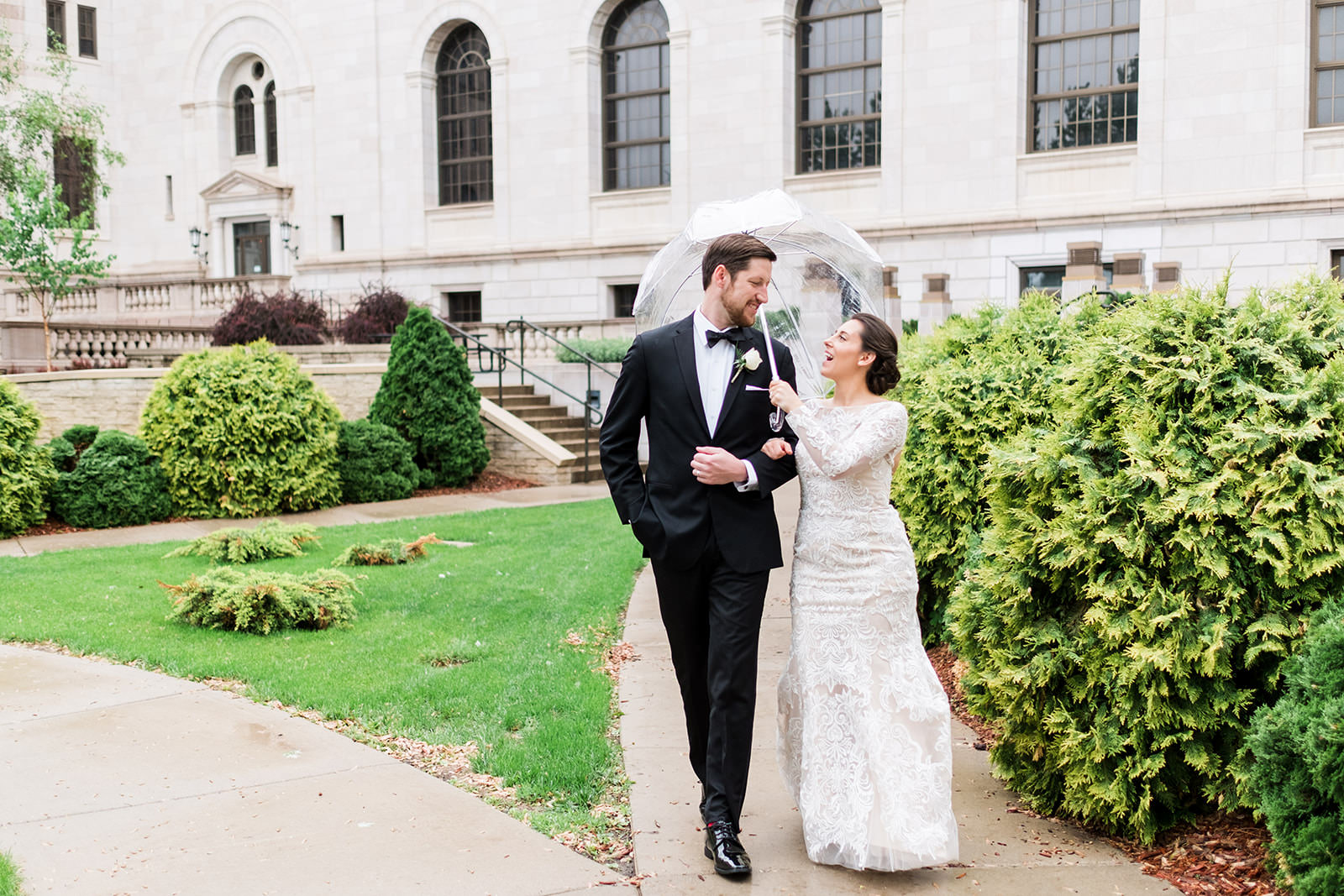 Couple walking in the rain with an umbrella laughing outside a stone building — St. Paul — Tim Larsen Photography, Brainerd Lakes MN