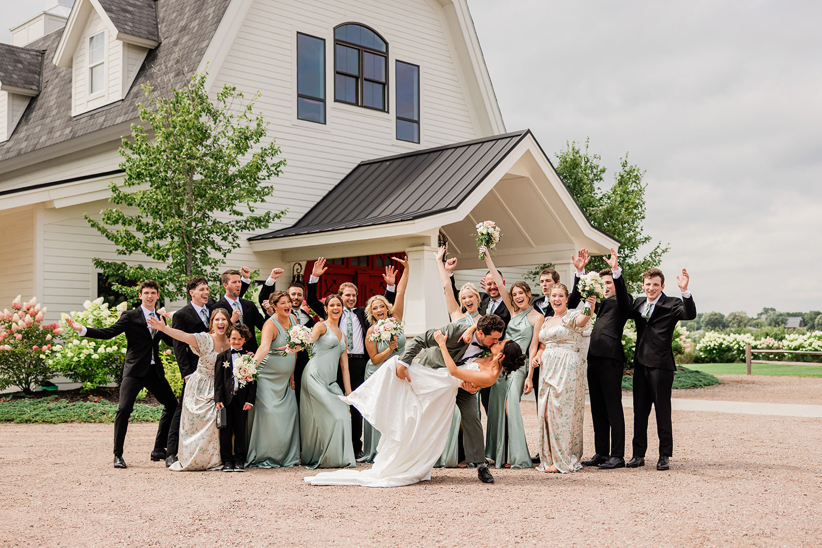 Wedding party celebrating outside a white farmhouse chapel — sage bridesmaids dresses — Tim Larsen Photography, Brainerd Lakes MN