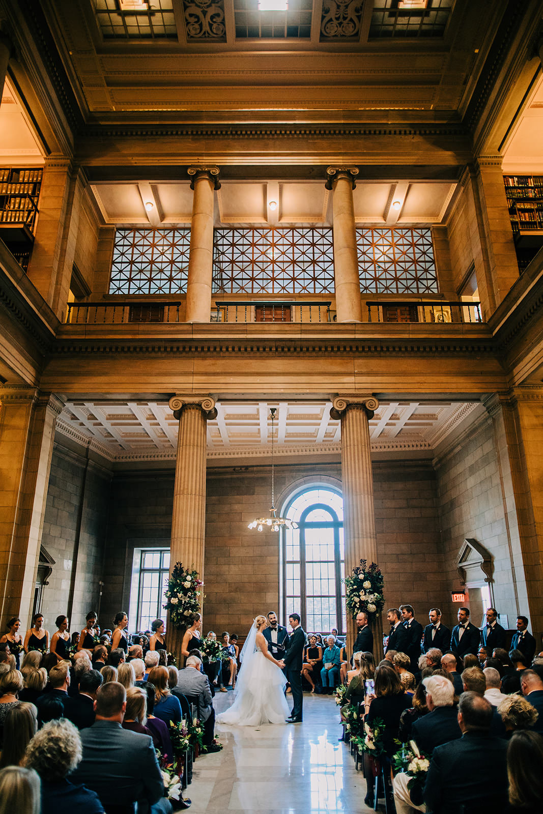 Ceremony in the James J. Hill Center library — tall columns, arched windows, and bookshelves — Tim Larsen Photography, Brainerd Lakes MN