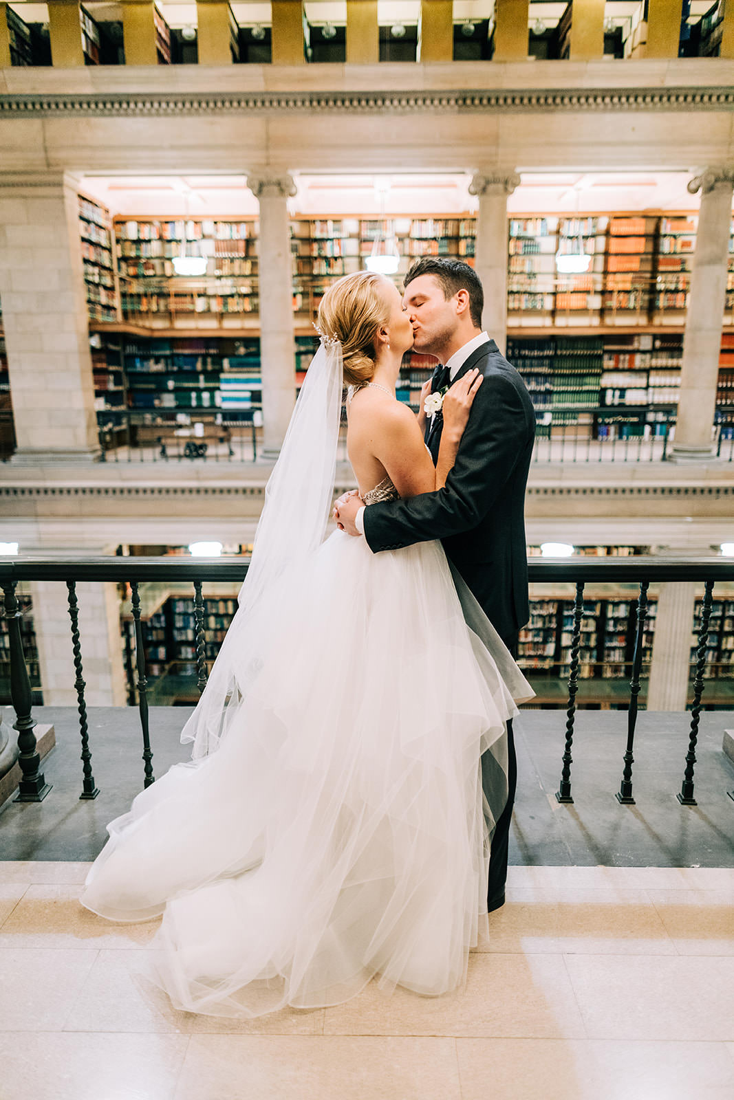 Couple kissing on the balcony of the James J. Hill Center with bookshelves behind them — Tim Larsen Photography, Brainerd Lakes MN