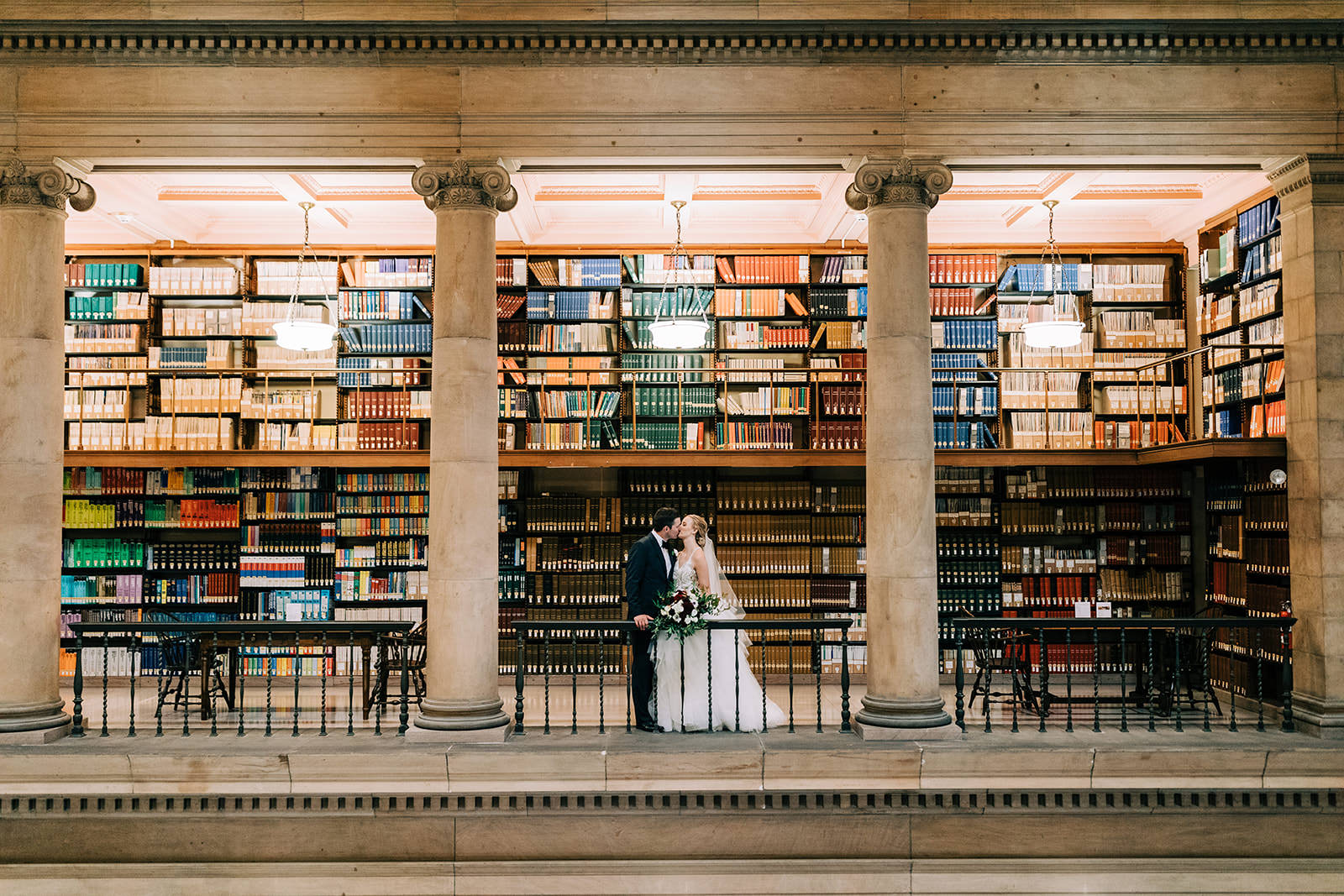 Couple kissing among library bookshelves and columns — James J. Hill Center Minneapolis — Tim Larsen Photography, Brainerd Lakes MN