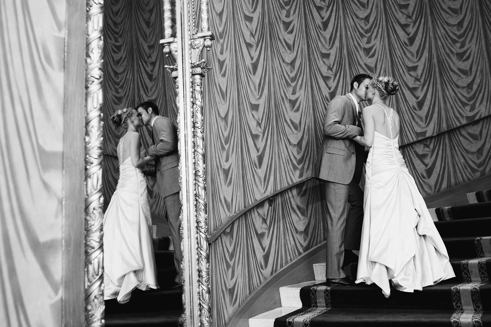 Couple kissing on a curved staircase reflected in a mirror — black and white editorial portrait — Tim Larsen Photography, Brainerd Lakes MN