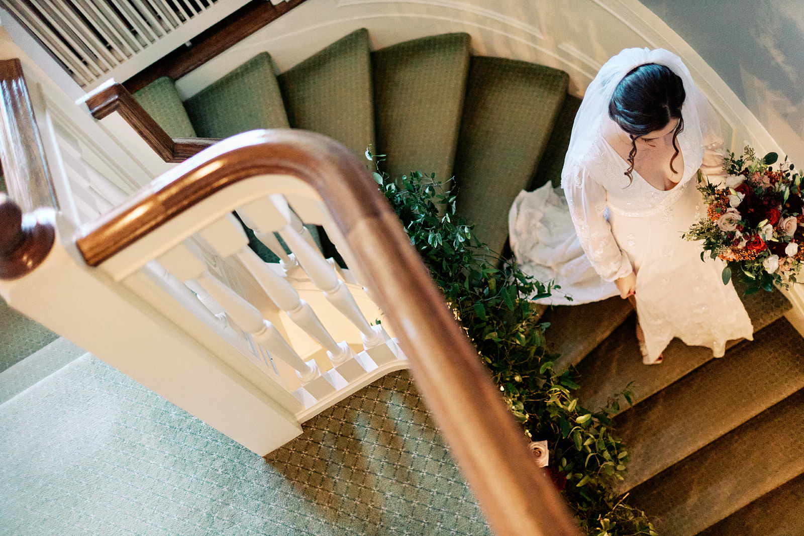 Bride descending a spiral staircase with greenery garland — overhead bridal portrait — Tim Larsen Photography, Brainerd Lakes MN