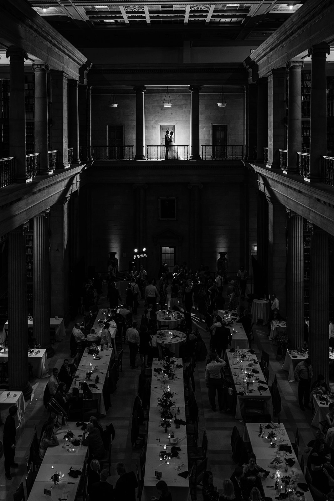 Reception dinner in a historic Minneapolis hall — long tables with candles and balcony above — Tim Larsen Photography, Brainerd Lakes MN