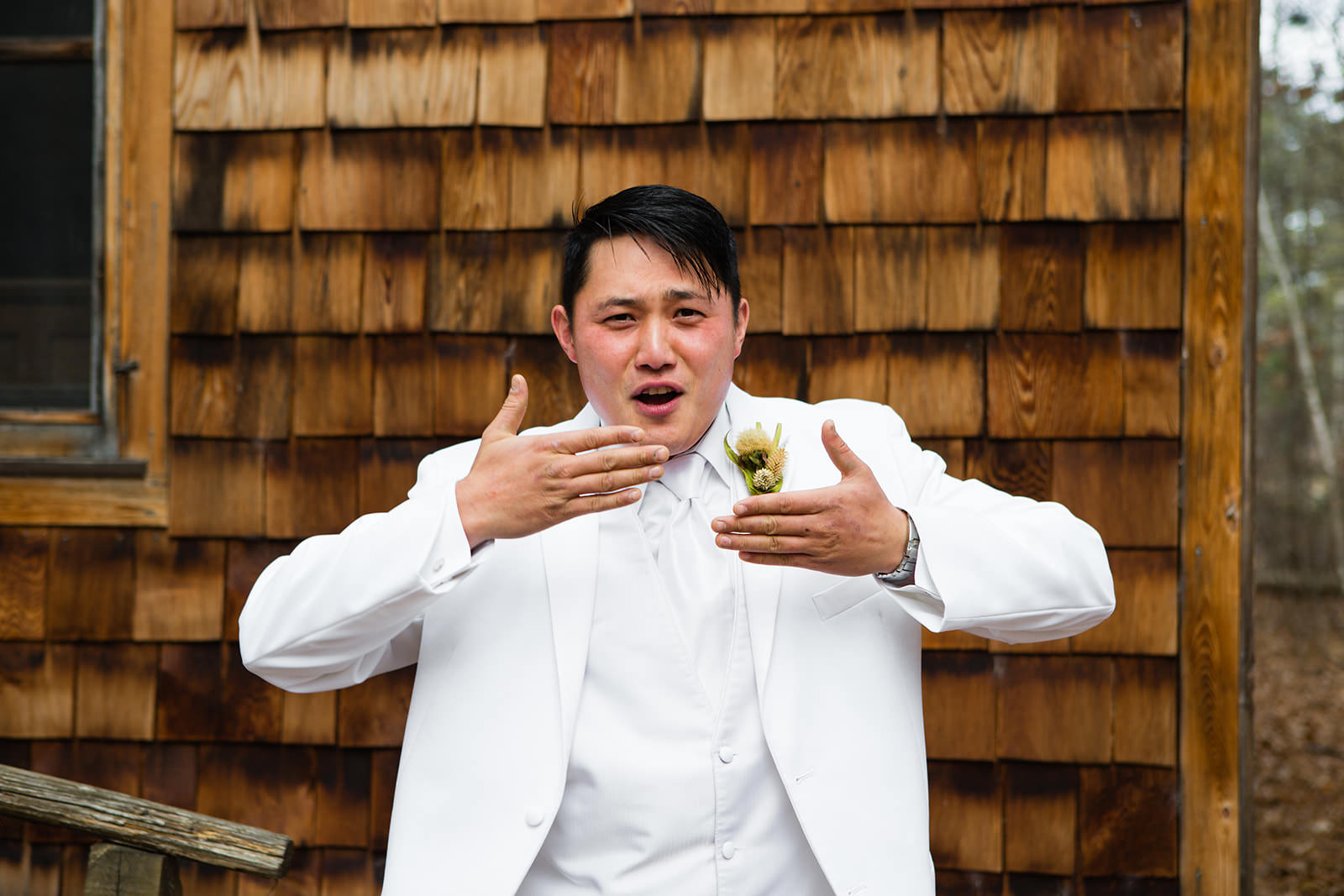 Groom adjusting boutonniere outside cedar-sided cabin at Whitefish Lodge — Tim Larsen Photography, Brainerd Lakes MN