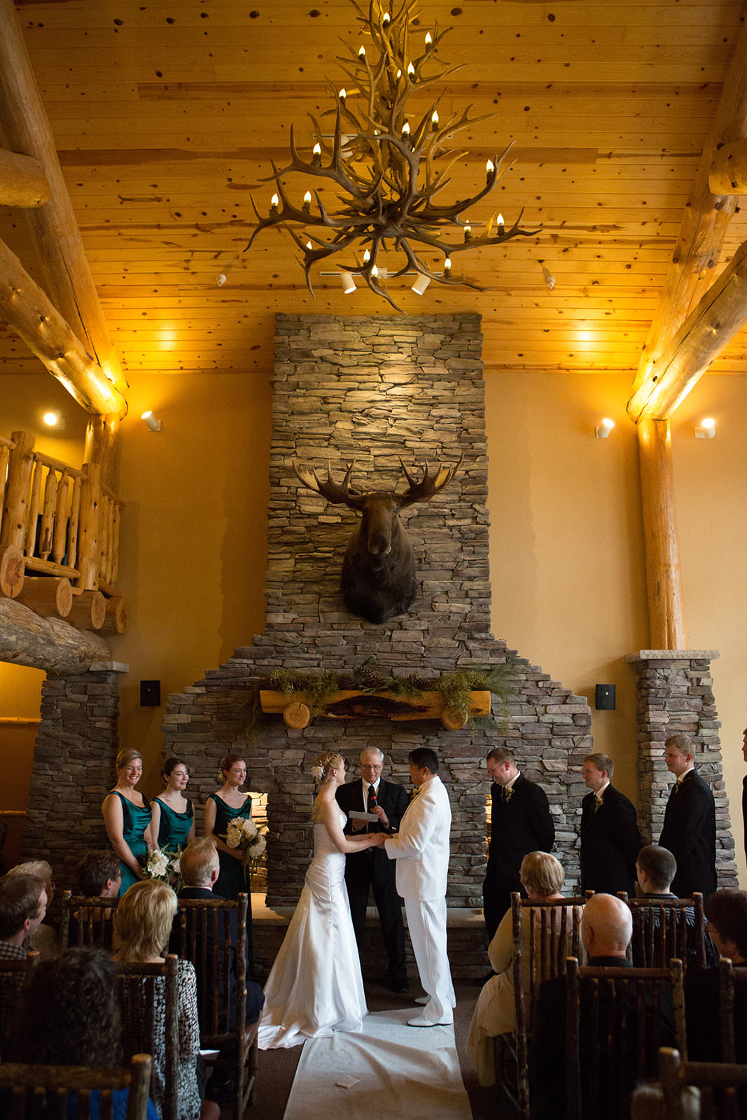 Indoor ceremony at Whitefish Lodge — stone fireplace, vaulted ceiling, antler chandelier — Tim Larsen Photography, Brainerd Lakes MN