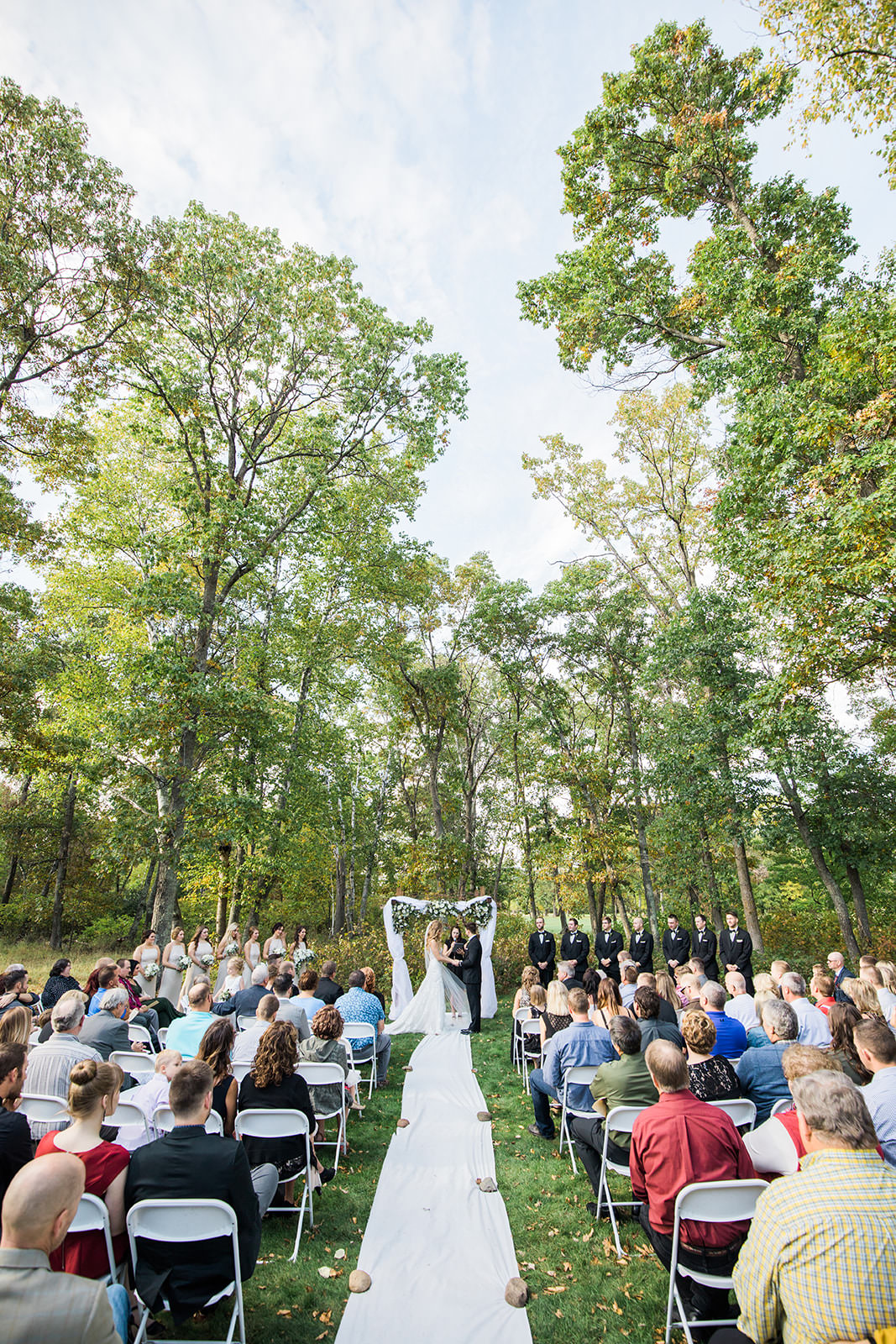 Outdoor ceremony on the grounds at Whitefish Lodge — tall trees and white chairs — Tim Larsen Photography, Brainerd Lakes MN