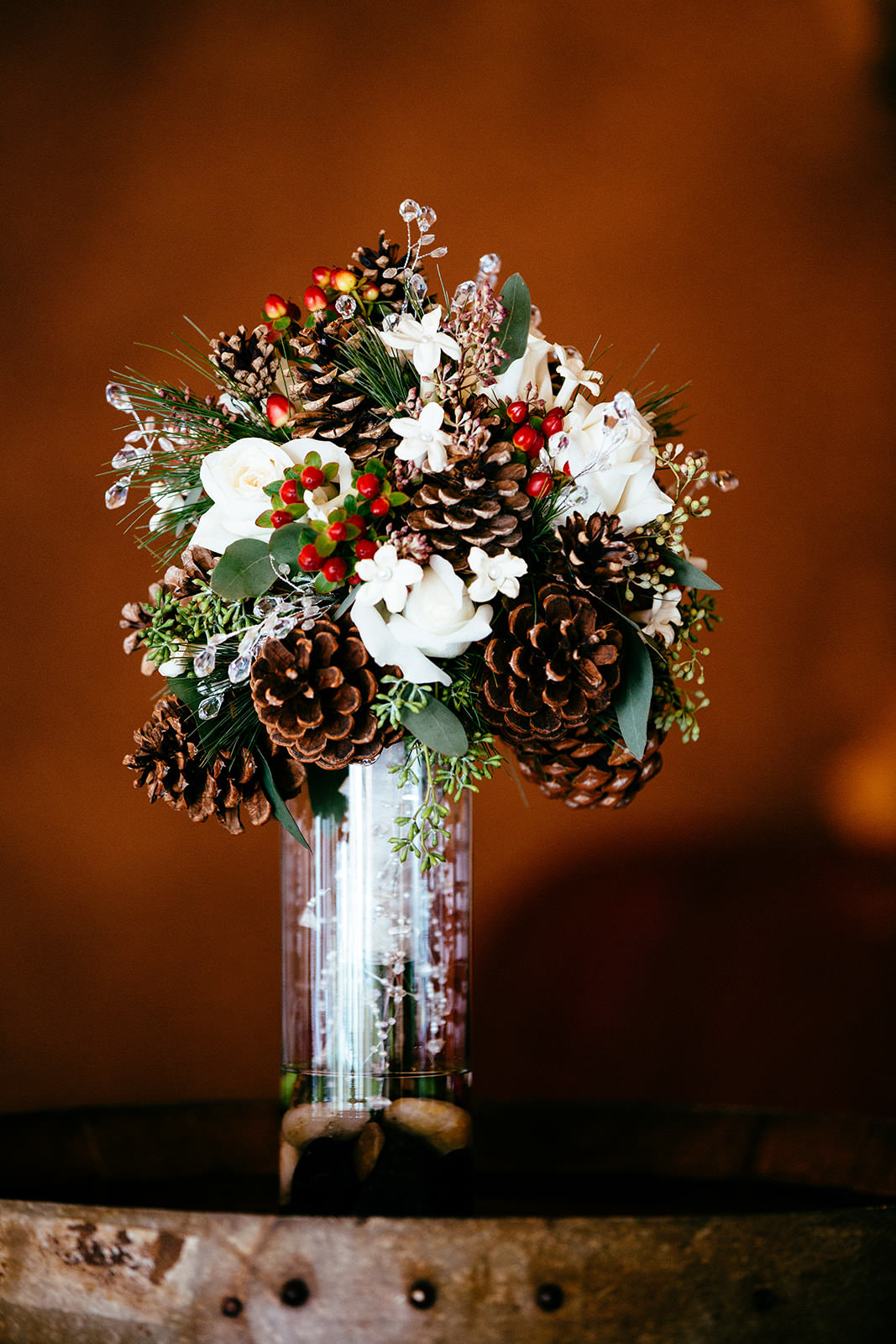 Winter bouquet with pine cones and white roses on a barrel at Whitefish Lodge — Tim Larsen Photography, Brainerd Lakes MN