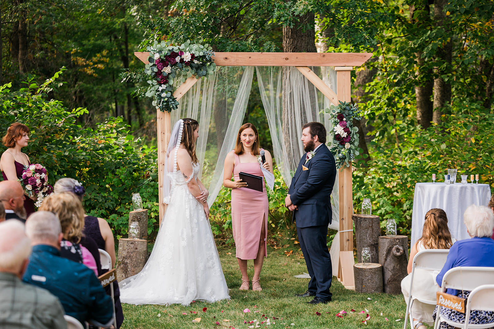 Outdoor ceremony under wooden arbor with flowers on the Whitefish Lodge grounds — Tim Larsen Photography, Brainerd Lakes MN