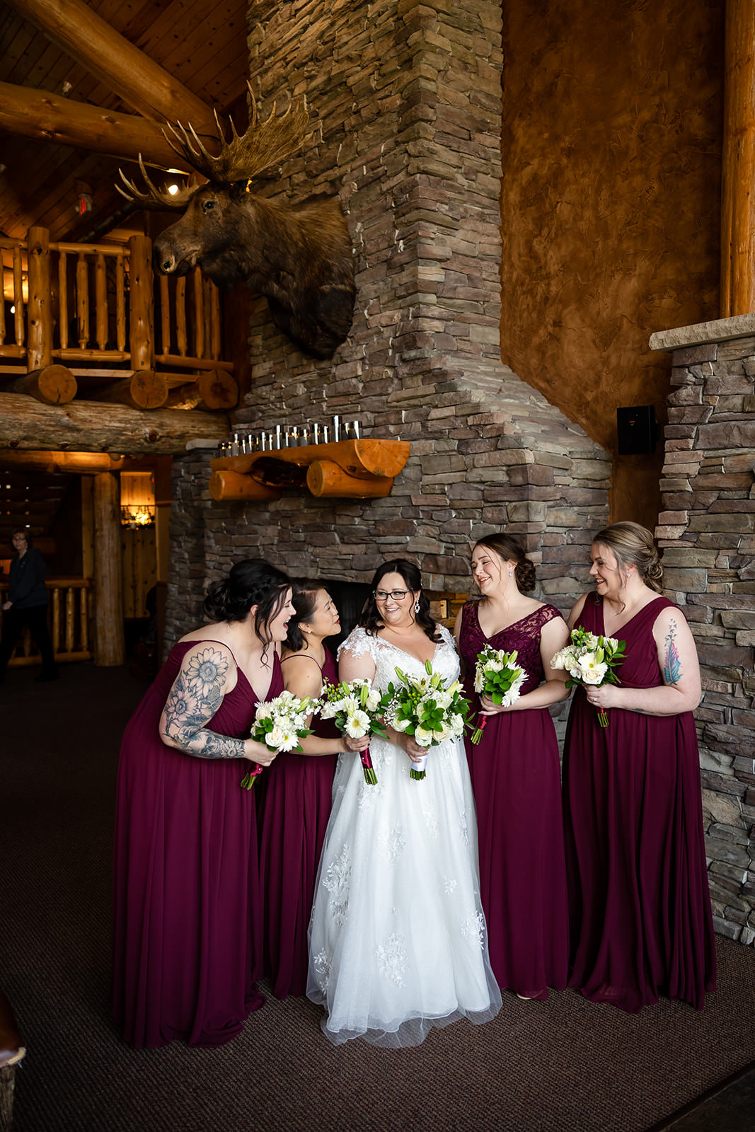 Bride with bridesmaids in front of the stone fireplace — burgundy dresses at Whitefish Lodge — Tim Larsen Photography, Brainerd Lakes MN