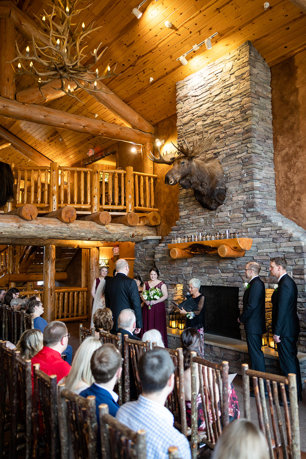 Indoor ceremony at stone fireplace — antler chandelier and log balcony at Whitefish Lodge — Tim Larsen Photography, Brainerd Lakes MN