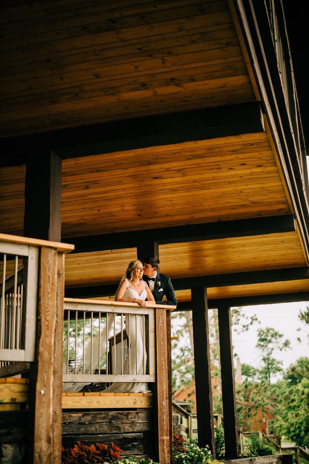 Couple framed small under massive warm-toned wood ceiling, deep negative space above. — Tim Larsen Photography, Brainerd Lakes MN